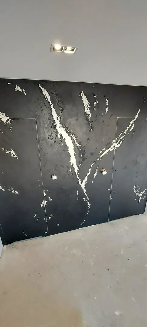 Czarny panel ścienny z białymi żyłkami i dwoma ukrytymi drzwiczkami, aranżacja wnętrz