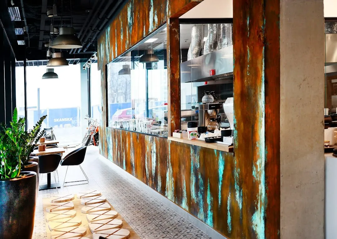 Nowoczesne wnętrze kawiarni z metalowymi panelami, stolikami i wzorzystymi płytkami – aranżacja wnętrz, układanie płytek