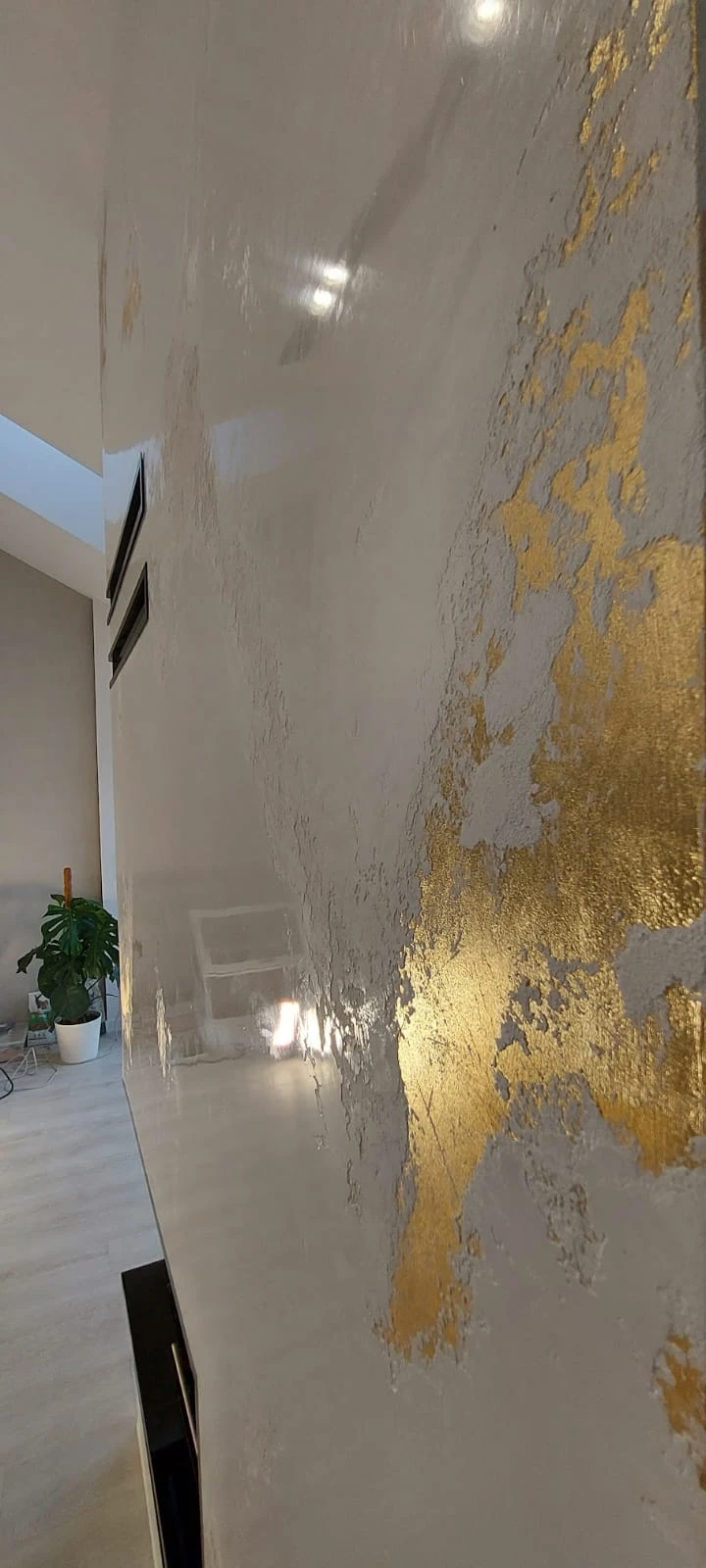 Dekoracyjny tynk strukturalny z metalicznym złotym akcentem na gładkiej ścianie