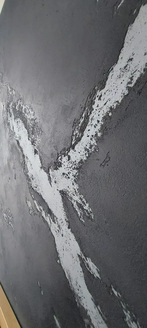 Szara ściana z widocznym efektem szpachlowania – białe pasy masy wyrównawczej