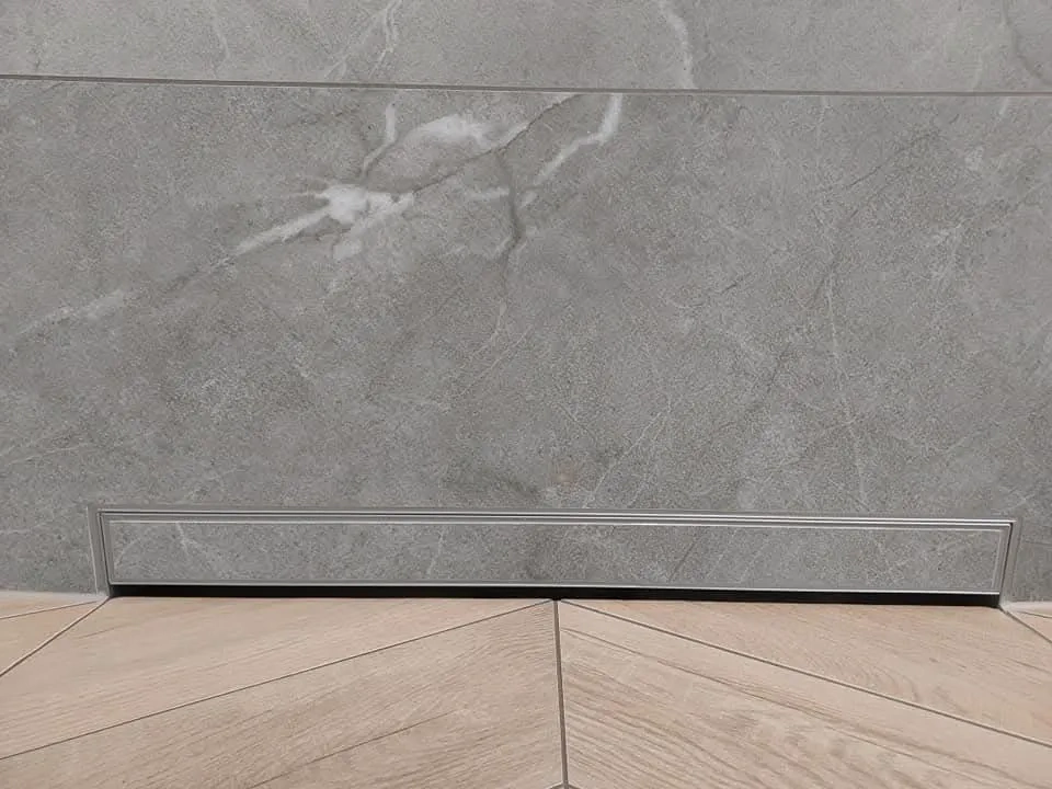 Szara płytka ścienna i drewnopodobne płytki podłogowe z metalowym odpływem liniowym – Układanie płytek