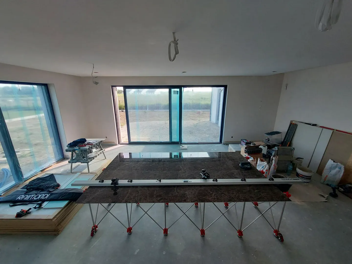 Układanie płytek wielkoformatowych na stelażu poziomującym w świeżo wyremontowanym pokoju z panoramicznymi oknami