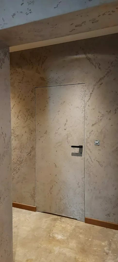 Ukryte drzwi w ścianie z dekoracyjnym tynkiem Montaż drzwi