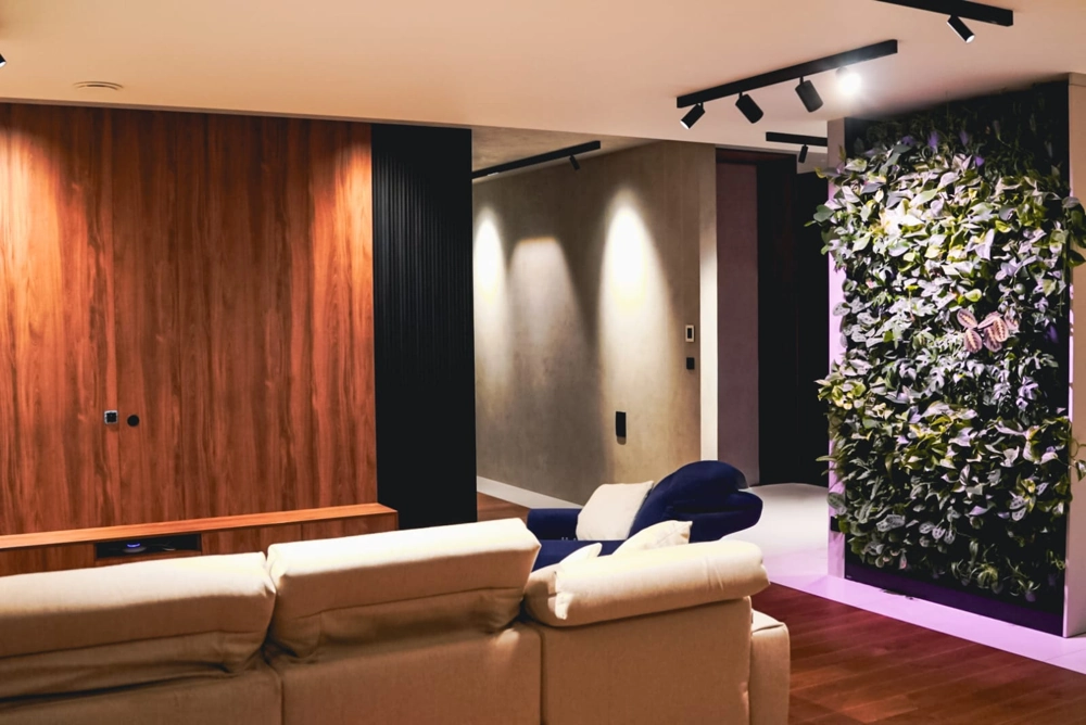 Salon z beżową sofą, drewnianą ścianą telewizyjną i zieloną ścianą roślinną – aranżacja wnętrz