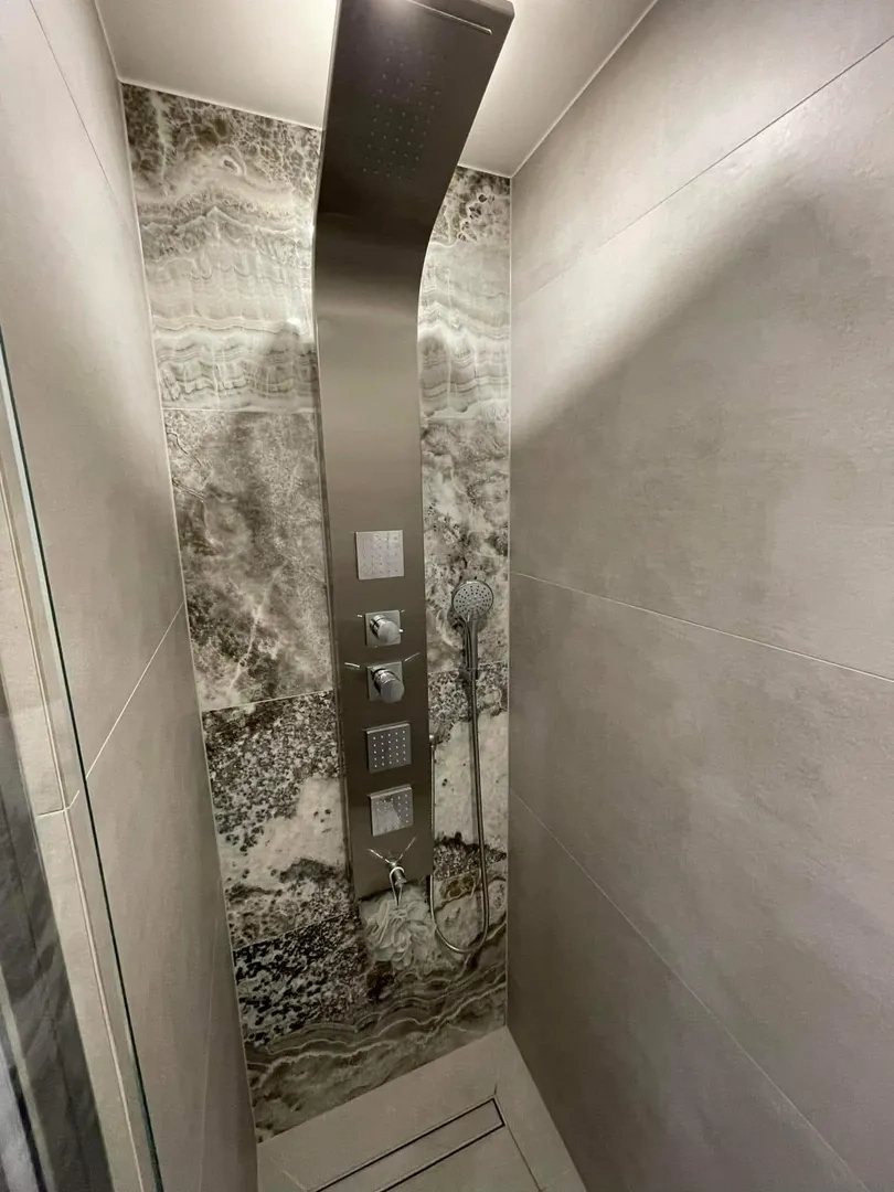 Kabina prysznicowa z panelem prysznicowym i szarymi płytkami wielkoformatowymi – remont łazienki