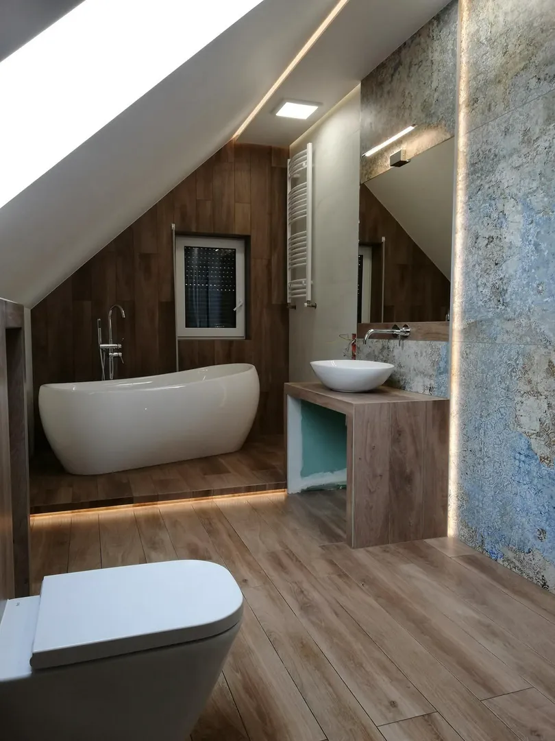 Nowoczesna łazienka na poddaszu z wolnostojącą wanną, umywalką nablatową, oświetleniem LED i drewnopodobnymi panelami – Remont łazienki