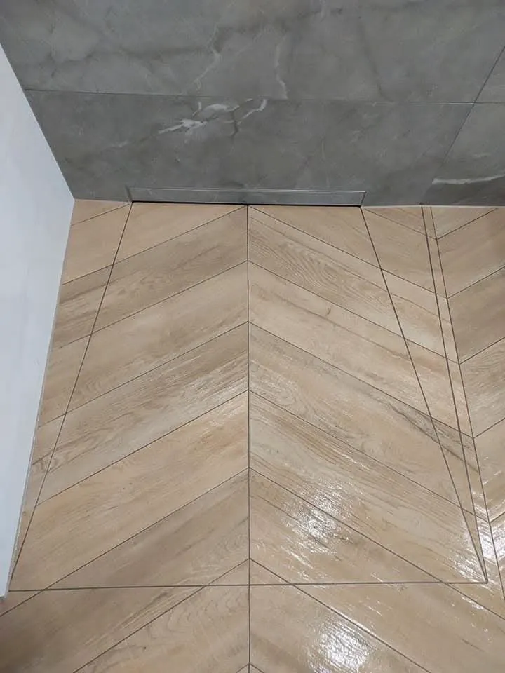 Beżowe płytki ułożone w jodełkę przy ścianie układanie płytek