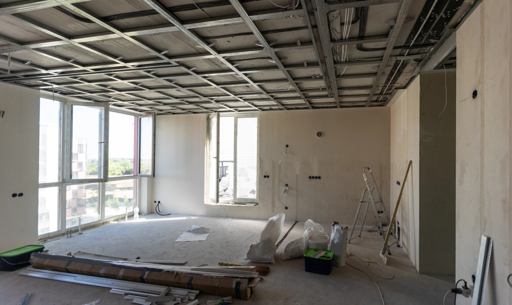 Rozłożona konstrukcja sufitów podwieszanych w pustym, remontowanym mieszkaniu z narzędziami na podłodze