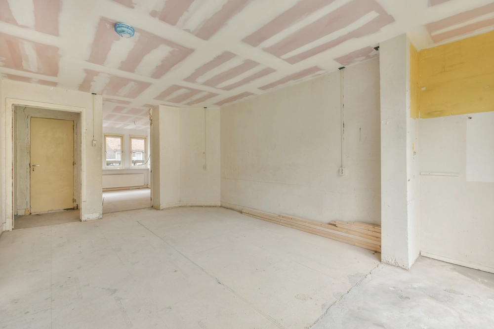 Pusty pokój w trakcie montażu sufitów podwieszanych, widoczne płyty gipsowe z nałożonymi spoinami