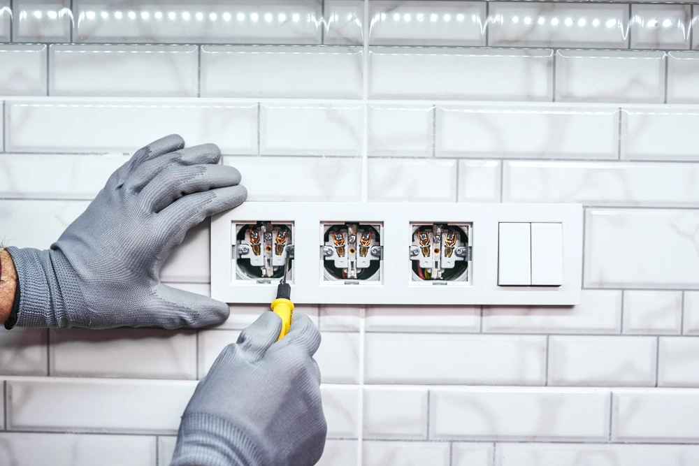 Montaż gniazdek elektrycznych na ścianie wyłożonej białymi kafelkami – Instalacje elektryczne